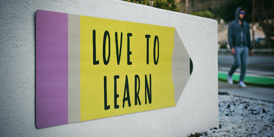 love to learn sign yellow wall