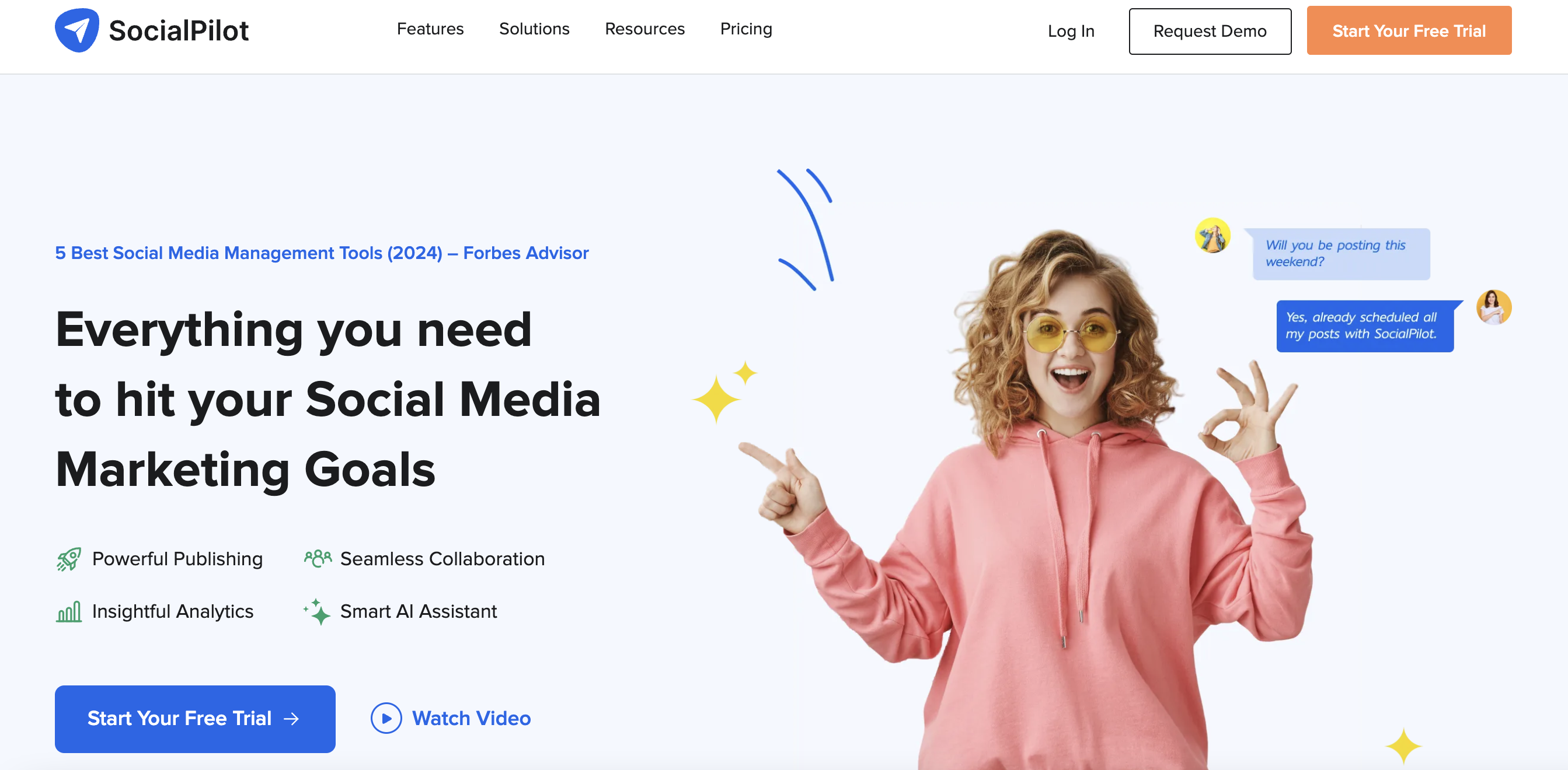 socialpilot homepage with a woman wearing a pink hoodie making an "ok" sign with one hand and another hand pointing at text that reads "everything you need to hit your social media marketing goals" 