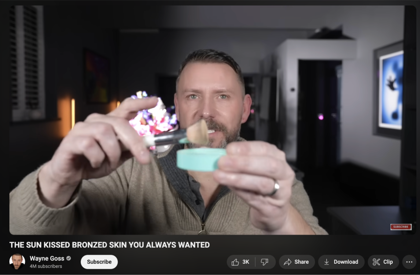 Wayne Goss holding bronzer and a brush in a YouTube tutorial