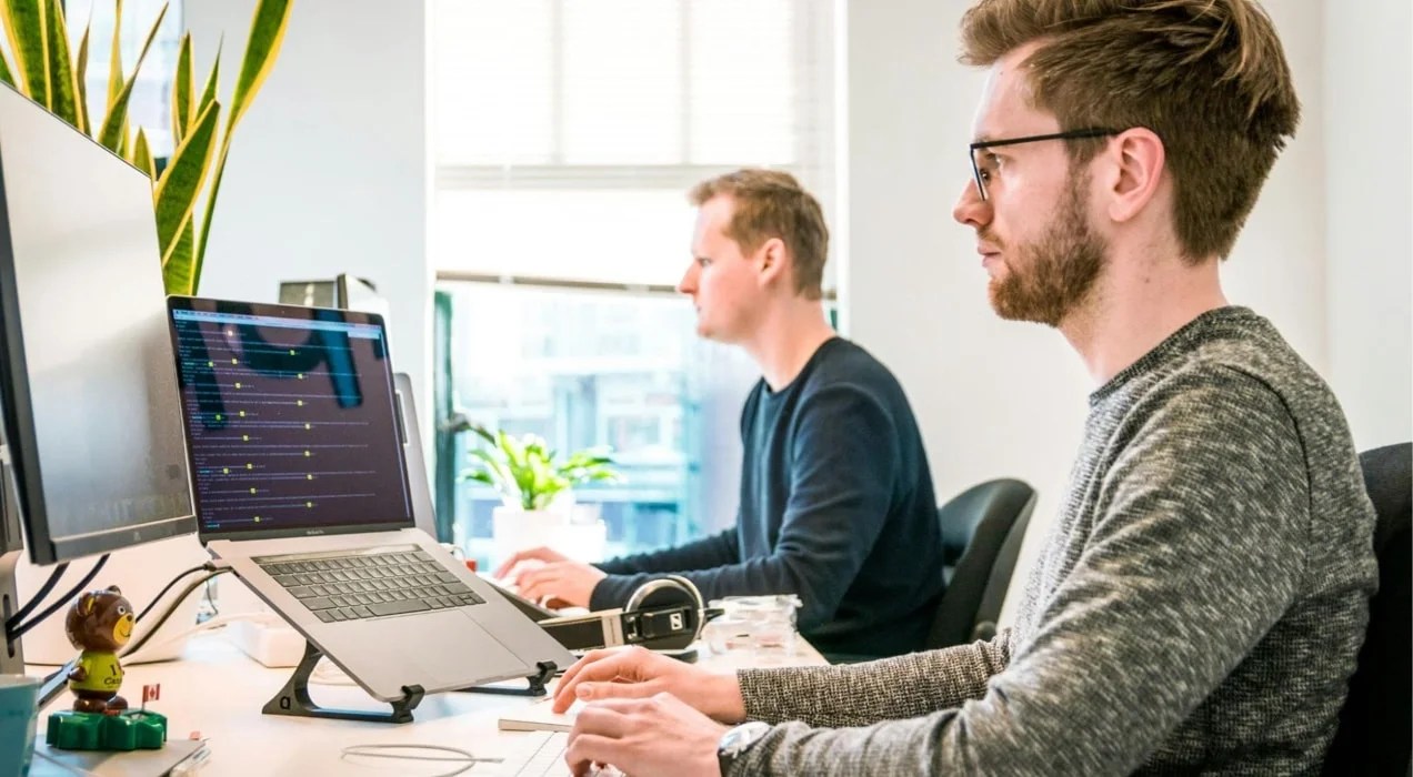 two men working at a desk in front of computers