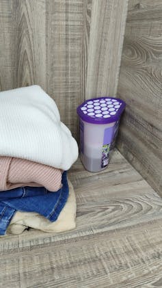 A shelf in a wardrobe with a purple box with white powder inside in the corner.