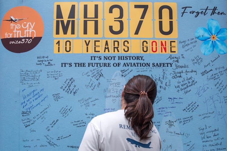 A woman in front of a memorial for flight MH370.