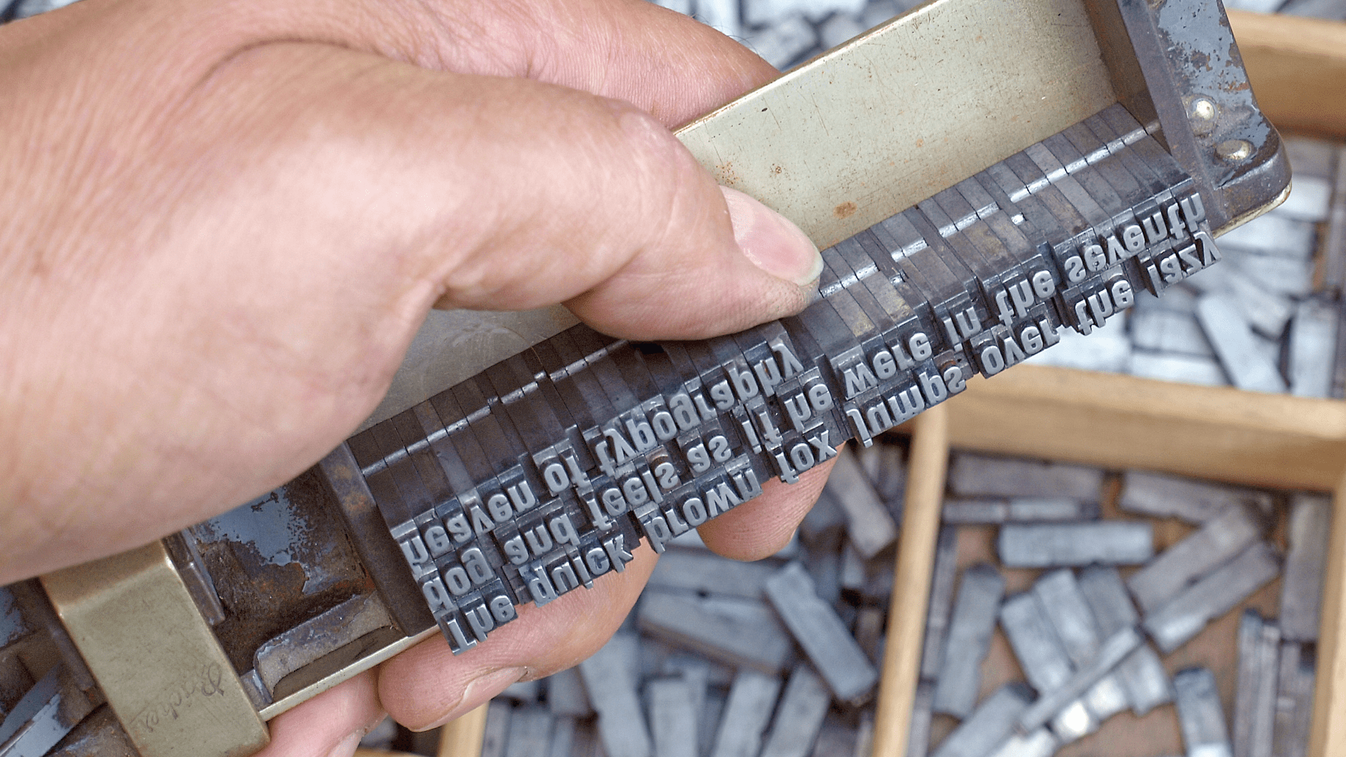 Closeup photo of a hand holding a metal type template for lettering.