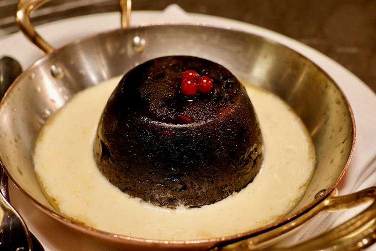 A christmas pudding sits in a dairy bath.